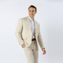 A man wearing a light beige three-piece suit with a white dress shirt and a brown belt, standing against a plain white studio background.