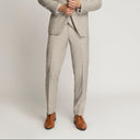 Man wearing a light gray suit with a white shirt and brown shoes on a plain background